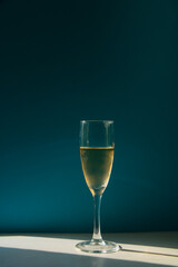 Transparent, beautiful glass with champagne stands on a white table on a blue background
