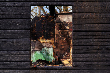 charred wooden window of a burnt house in countryside