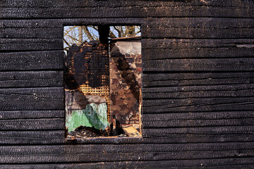 charred wooden window of a burnt house in countryside