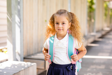 Happy little schoolgirl with school bag in school garden. Back to school outdoor