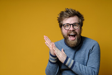 Satisfied man with disheveled hair and a beard rejoices and rubs his palms with a happy expression...