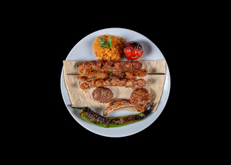 Served with traditional lamb chops, kebabs, meatballs, mixed grilled tomatoes, peppers and rice cooked on the grill. service with white plate. Grilled lamb with vegetables on the grill top view. 