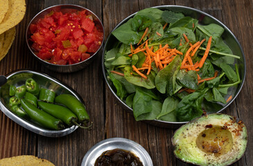 Greens, chili, avocado and chopped tomatoes for tostada making