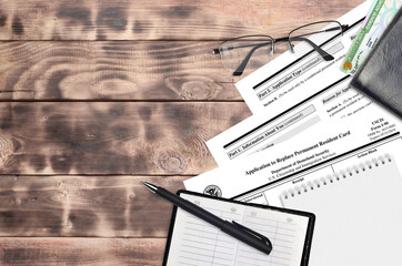 USCIS form I-90 Application to replace permanent resident card lies on flat lay office table and...