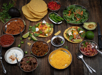Vegetarian corn tostada with a variety of side toppings on wooden table