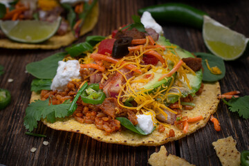 Vegetarian corn tostada with a variety of side toppings on wooden table
