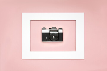 Fototapeta premium Flat lay old analog camera in the paper white frame on pink background