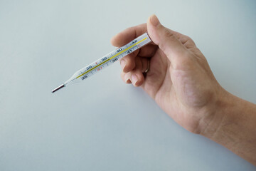 Thermometer in a woman's hand isolated on clean background. Temperature measuring.