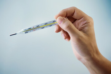 Thermometer in a woman's hand isolated on a clean background. Temperature measuring. Fever...