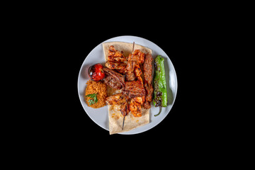 Served with traditional lamb chops, kebabs, meatballs, mixed grilled tomatoes, peppers and rice cooked on the grill. service with white plate. Grilled lamb with vegetables on the grill top view. 