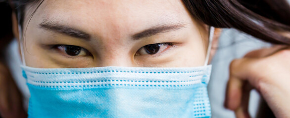 Asian girl wears a face mask that protects against the spread of coronavirus disease. Close- up of a young woman with a surgical mask on her face against Covid-19.