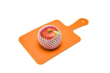 Apple in a protective grid on a cutting board on a white background