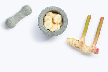 Fresh galangal slices in stone mortar with pestle on white