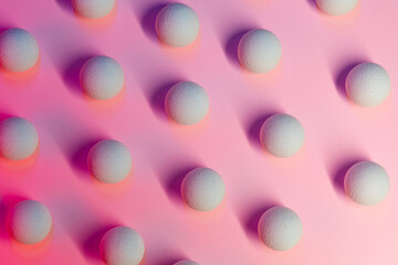 Colored light shines on white balls on a pink background.