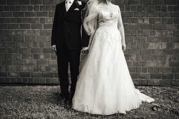 Black and white photo of wedding couple. Bride and groom in wedding clothes holding hands. Without head. Wedding day concept.