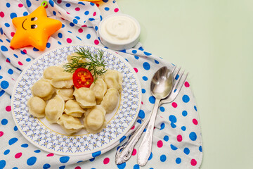 Hot meat dumplings with fresh sour cream. Homemade healthy kid's food, funny toys