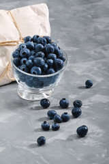 Blueberries on a black background,, fresh berry in a bowl on a concrete background with a wrapped envelope with a berry. copies of space, delivery of berries.