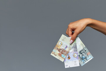 Beautiful female hands hold the Catalan rial on a gray background. Copy space, gray background