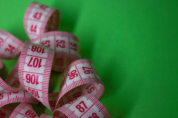 Close up of Red measuring tape on green background. Loss weight concept. Top view. Copy space. Isolated. High quality photo