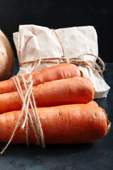Fresh carrots, dark background. Food delivery concept, eco-friendly packaging. Copy space, close-up