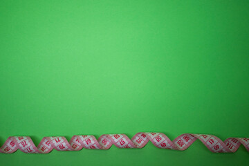 Red measuring tape on green background. Loss weight concept. Top view. Copy space. Isolated. . High quality photo