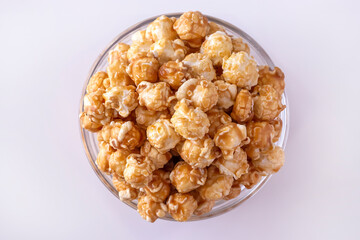 Sweet caramel popcorn in glass bowl. Close up. White background. Top view.
