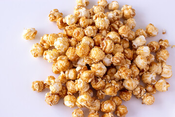 Heap of sweet caramel popcorn in glass bowl. Close up. Light background.
