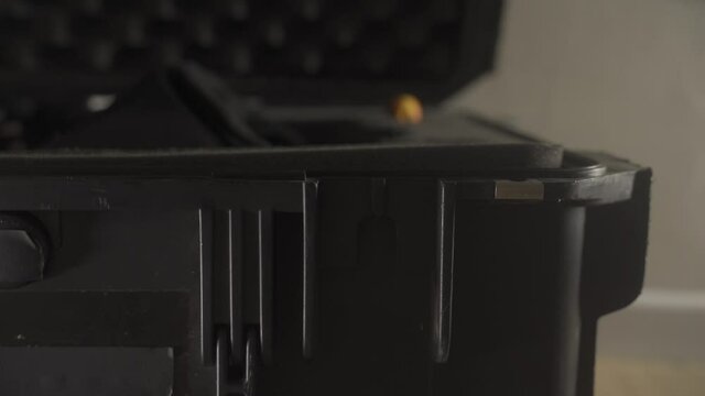 Hand with latex rubber glove opens and closes latch of professional hard case