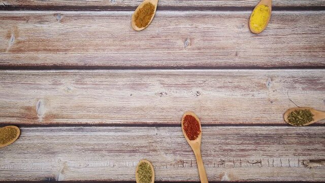 Eco friendly spoons with various spices appear on wooden table - Stop motion 
