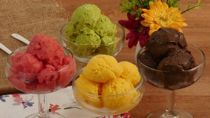 Sélection de saveurs gourmandes de glacesaux couleurs vives servies dans des tasses  individuelles sur une  table en bois rustique dans un glacier.