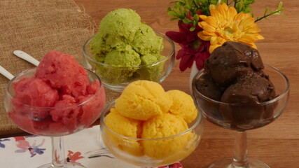 Sélection de saveurs gourmandes de glacesaux couleurs vives servies dans des tasses  individuelles sur une  table en bois rustique dans un glacier.