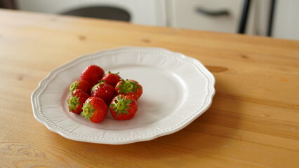 Close up of ripe strawberries on plate on table in kitchen.