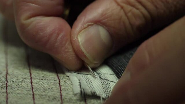 tailor sewing pants with needle and thread slow motion