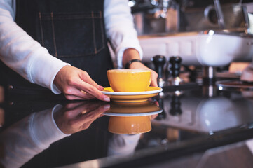 Coffee Business Concept.Asian woman wear blue apron holding hot coffee cup Submit to the customer
