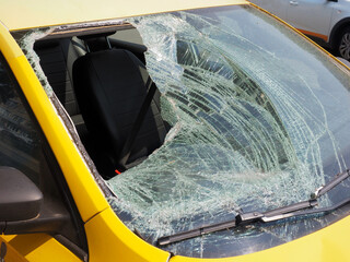 The broken windshield of the yellow car after hitting a man, pedestrian