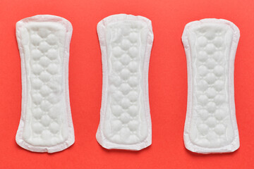 Three female pads on a red background.
