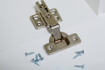 installation of furniture hinges in the new kitchen cabinet door or replace the hinges closeup. 