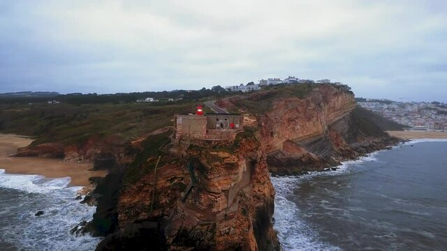 An iconic place on the Atlantic coast, the Mecca of big-wave surfing. View of Nazare's lighthouse in Zon North Canyon, place with the biggest waves in Europe, Nazare, Portugal