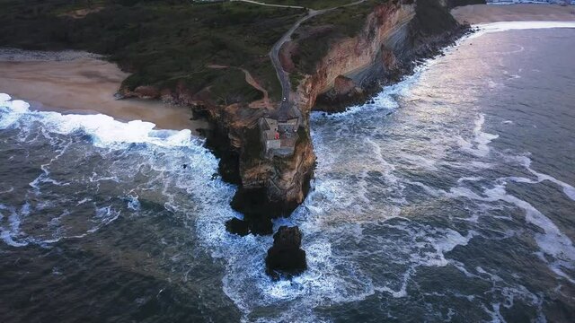 An iconic place on the Atlantic coast, the Mecca of big-wave surfing. View of Nazare's lighthouse in Zon North Canyon, place with the biggest waves in Europe, Nazare, Portugal