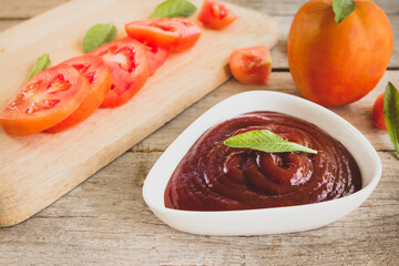 bowl of ketchup or tomato sauce and fresh tomatoes on Wooden table.
