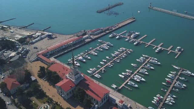 Aerial view of marine station near the city. Clip. Flying over summer seascape of the seaport with moored ships and yachts by the coastal town, water transport concept.