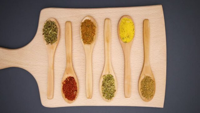 Eco friendly wooden spoons with various spices appear on cutting board - Stop motion 