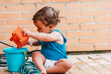 little boy playing with bucket and water at home confinement covid19