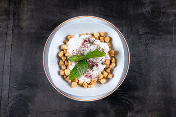 Plates of traditional Turkish food. Manti(Turkish ravioli) with yogurt sauce. Top view black wood background