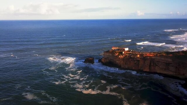 An iconic place on the Atlantic coast, the Mecca of big-wave surfing. View of Nazare's lighthouse in Zon North Canyon, place with the biggest waves in Europe, Nazare, Portugal