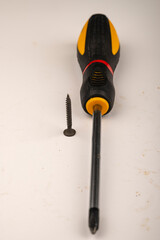 Screw and screwdriver on a white background. Close up. Manual locksmith and installation tools for home work.