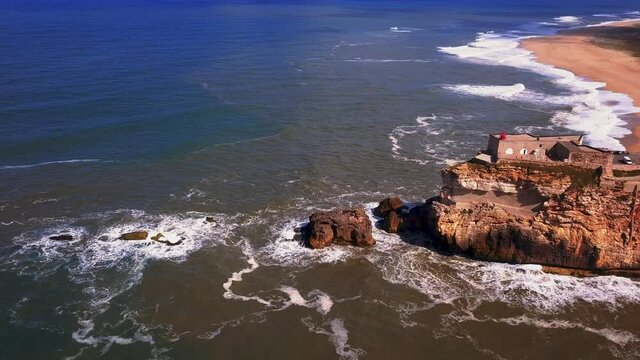An iconic place on the Atlantic coast, the Mecca of big-wave surfing. View of Nazare's lighthouse in Zon North Canyon, place with the biggest waves in Europe, Nazare, Portugal