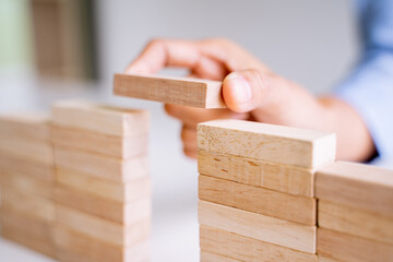 Close up of hand holding small wooden brick put on the wall, Risk and solution.