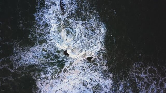 Waves crash against the rocks. An iconic place on the Atlantic coast, the Mecca of surfing on big waves.Rocks at the Nazare Lighthouse, the place with the largest waves in Europe, Nazare, Portugal