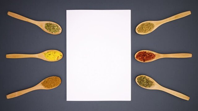 Wooden eco friendly spoons with spices appear around white paper for recipe - Stop motion 